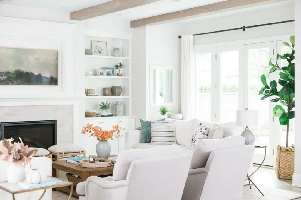 A living room with white furniture and wooden shelves.